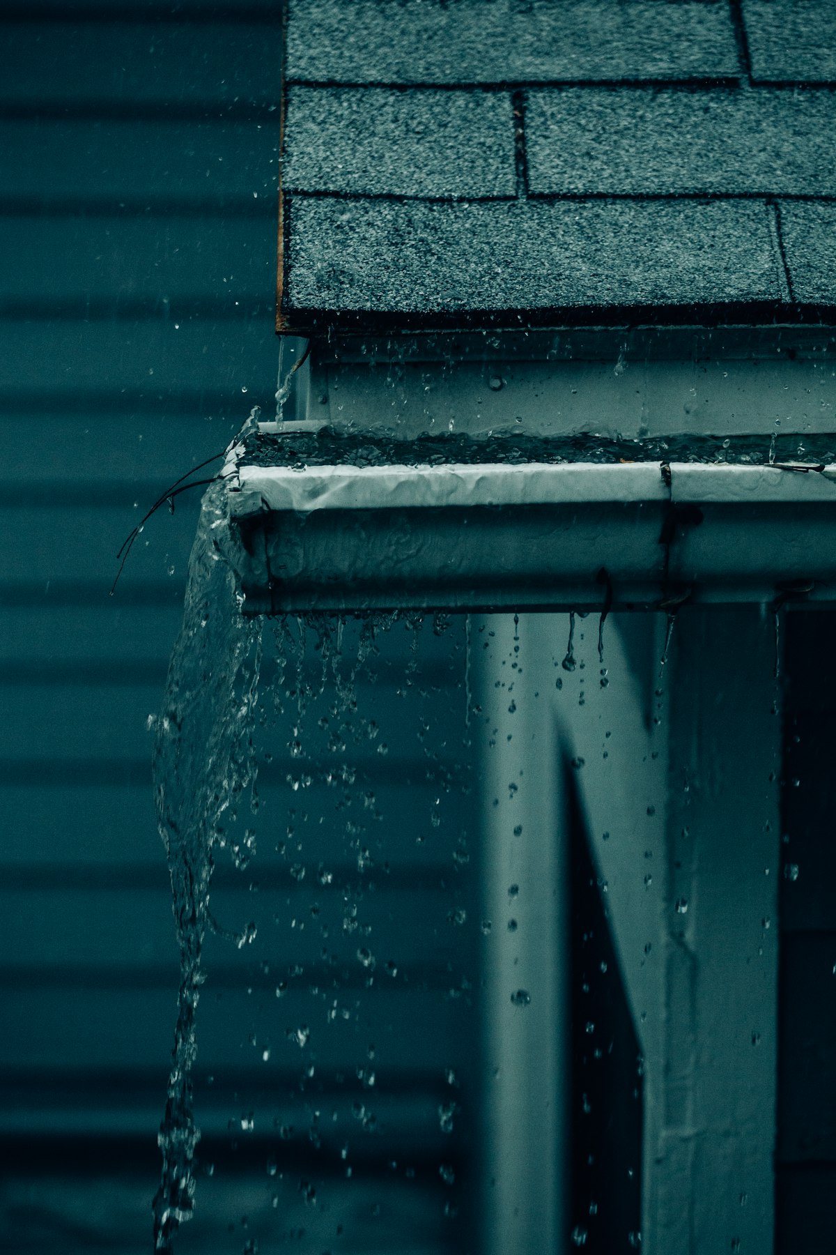 Rainwater flowing freely off a clean gutter and downspout